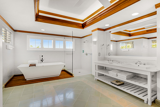 bathroom area with a tub, walk in shower, bench, and vanity with shelving underneath