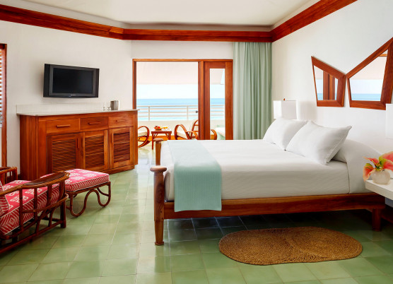 a guest room with white bed linens and a beach view from the balcony