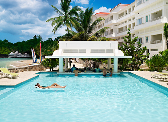 swim up pool bar at the resort with woman laying on a pool float in water