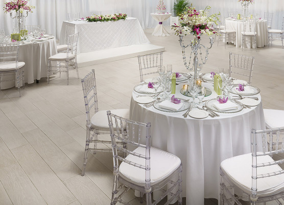 indoor wedding reception with round white tablecloth tables with centerpieces 