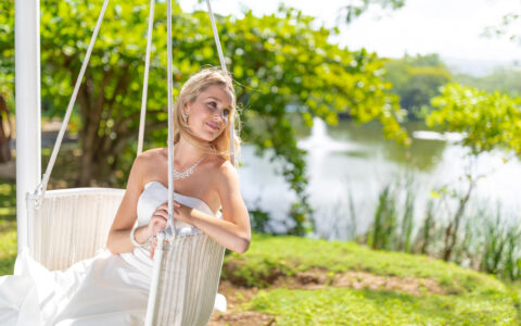 bride sitting in a white wicker swing looking off to the side