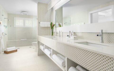 white bathroom decor with a glass shower, toilet, and vanity with two sinks