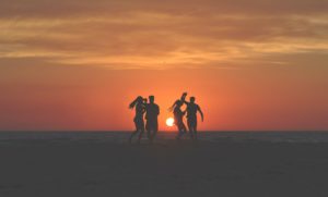 people dancing on a beach at sunset